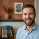 Portrait of a happy Dutch man with a well-groomed short beard, smiling confidently in a warm domestic setting.